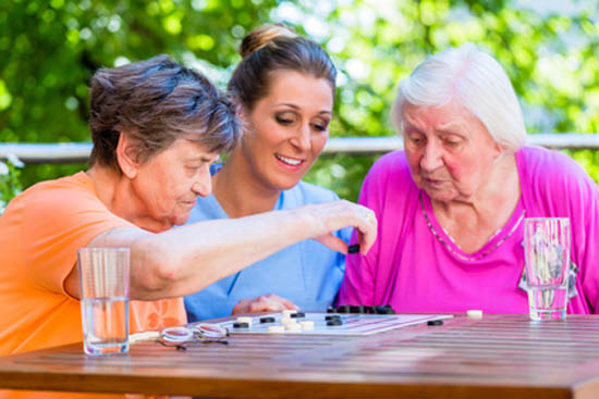 Two senior ladies playing board game in rest home